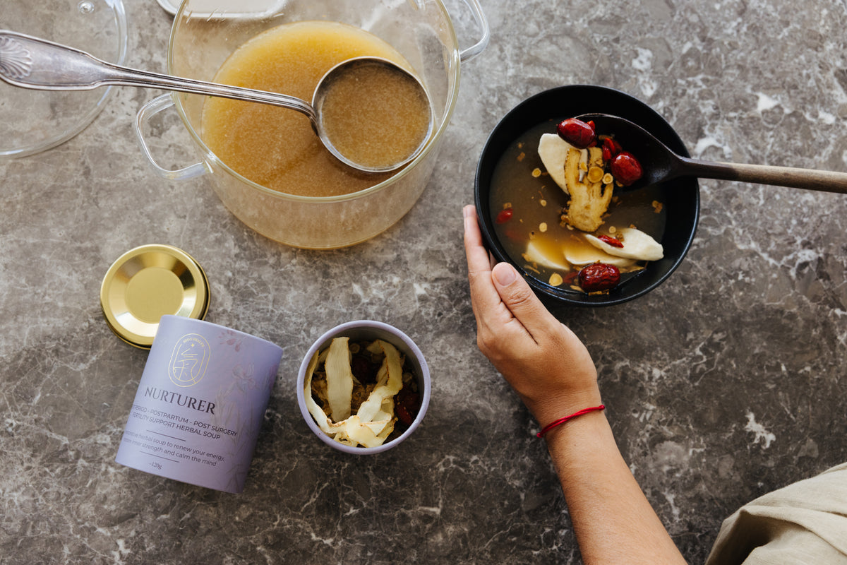 Segohealth soup nurturer person holding a bowl of food next to a pitcher of soup on a textured surface